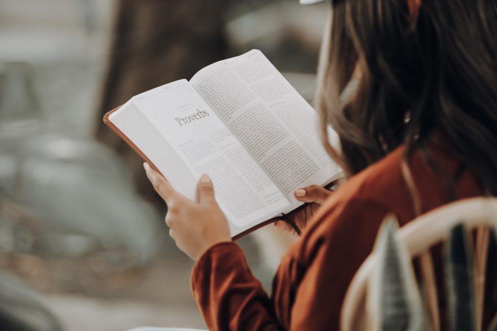 A woman is sitting in a chair reading a book.