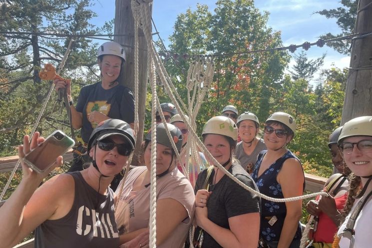 A group of people are standing next to each other on a ropes course.