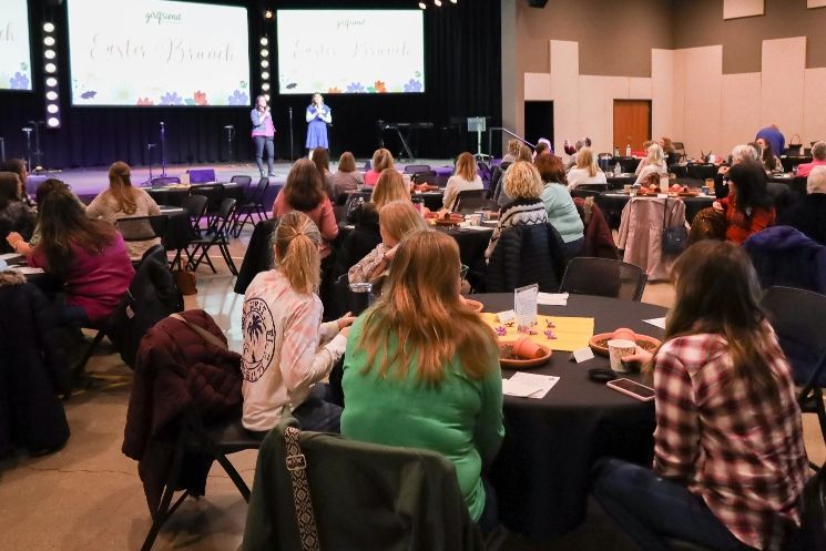 A large group of people are sitting at tables in a large room.