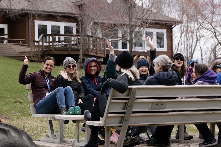 A group of people are sitting on a bench in front of a house.