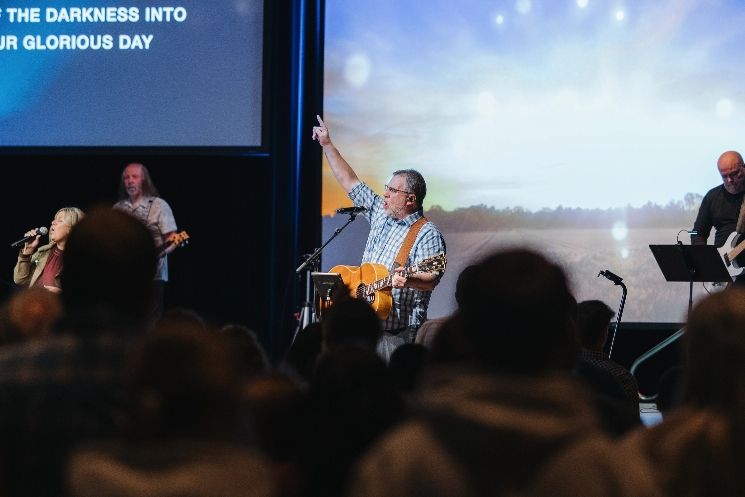 A man is playing a guitar in front of a crowd at a church.