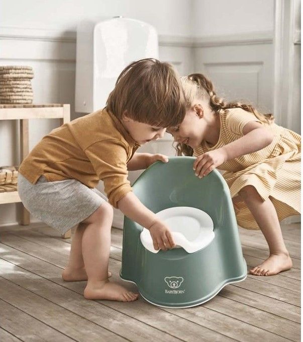 A boy and a girl are playing with a potty.
