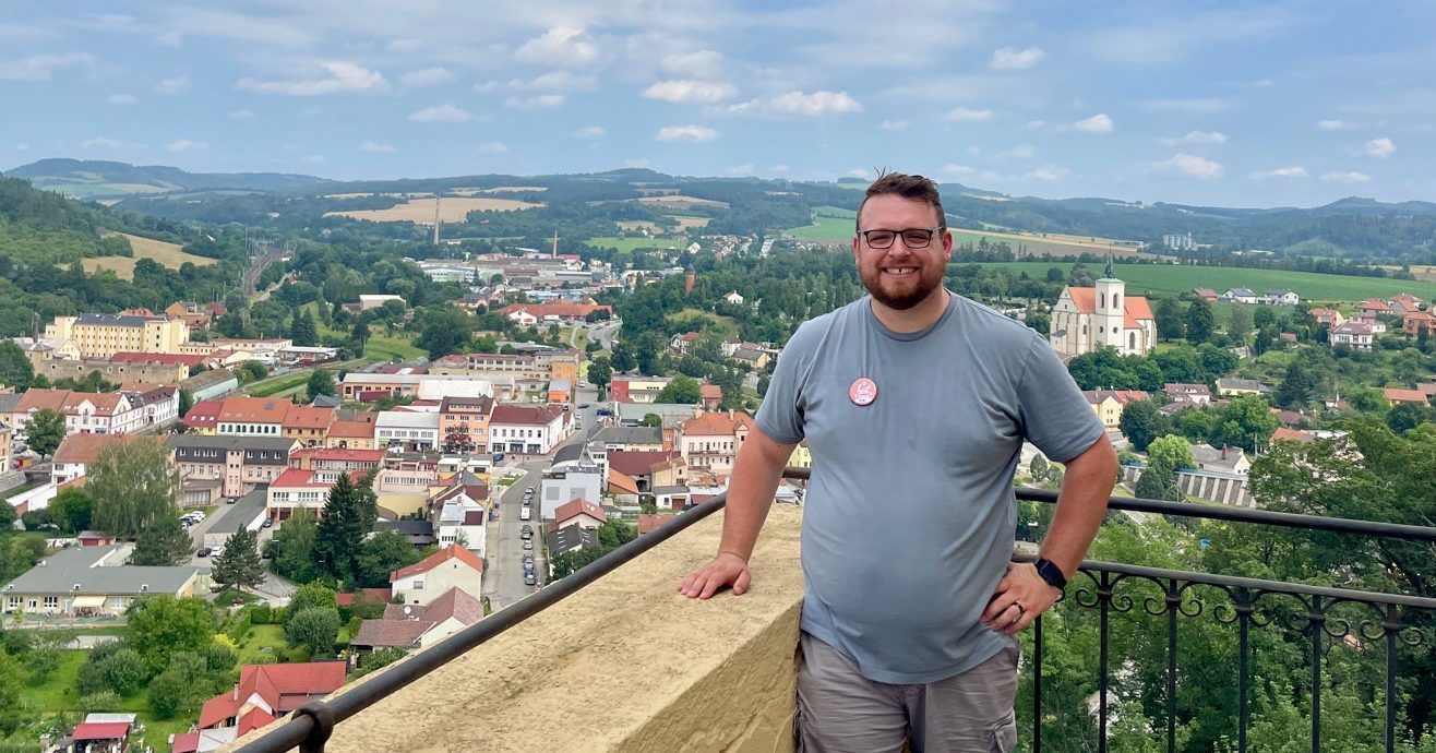 A man is standing on a balcony overlooking a city.
