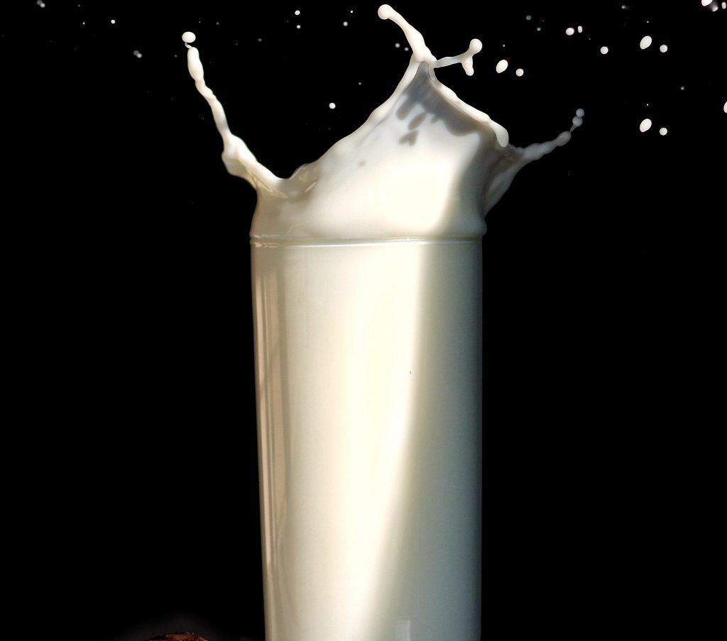 A glass of milk is splashing on a black background