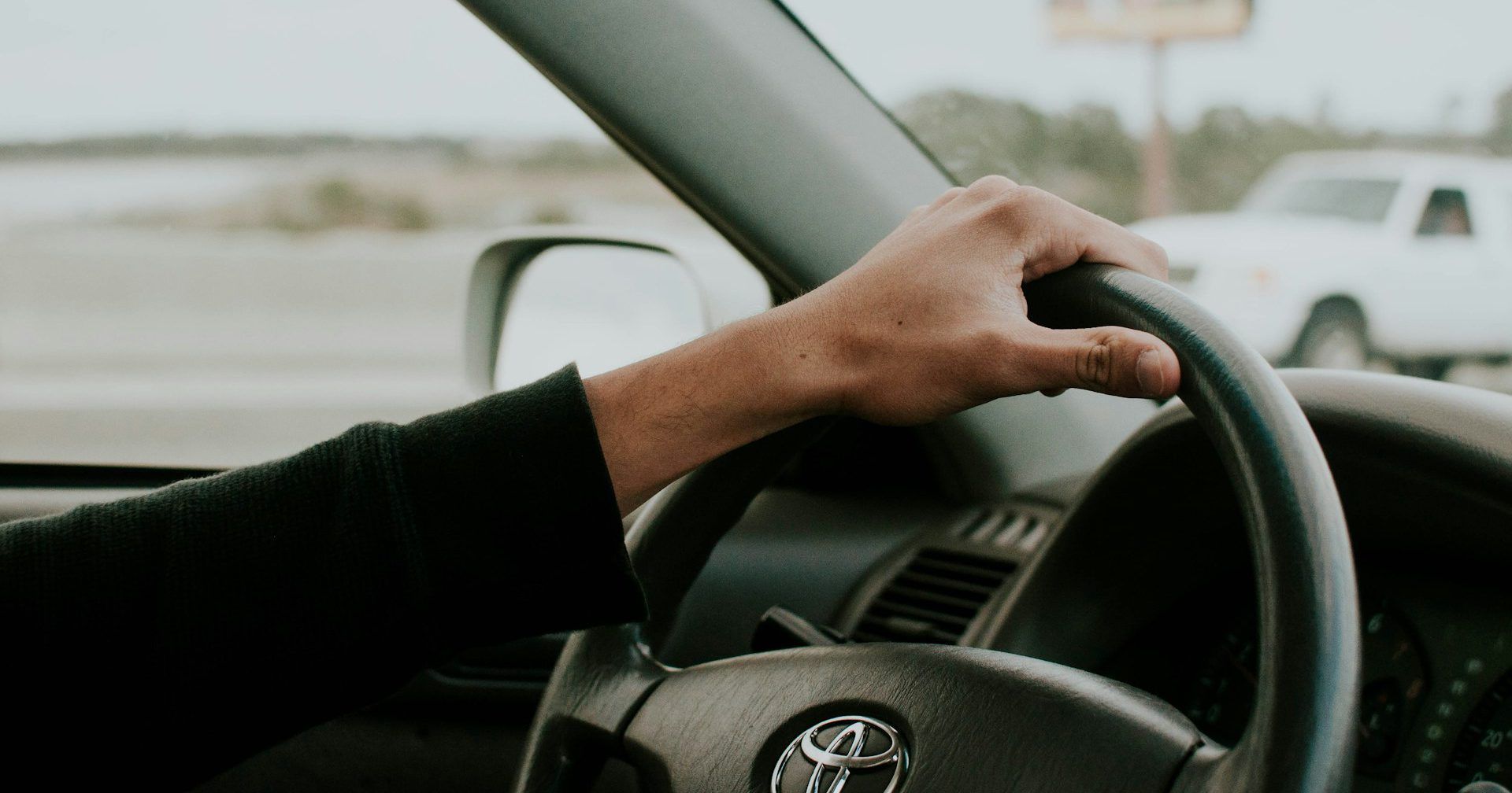 A person is holding the steering wheel of a car.