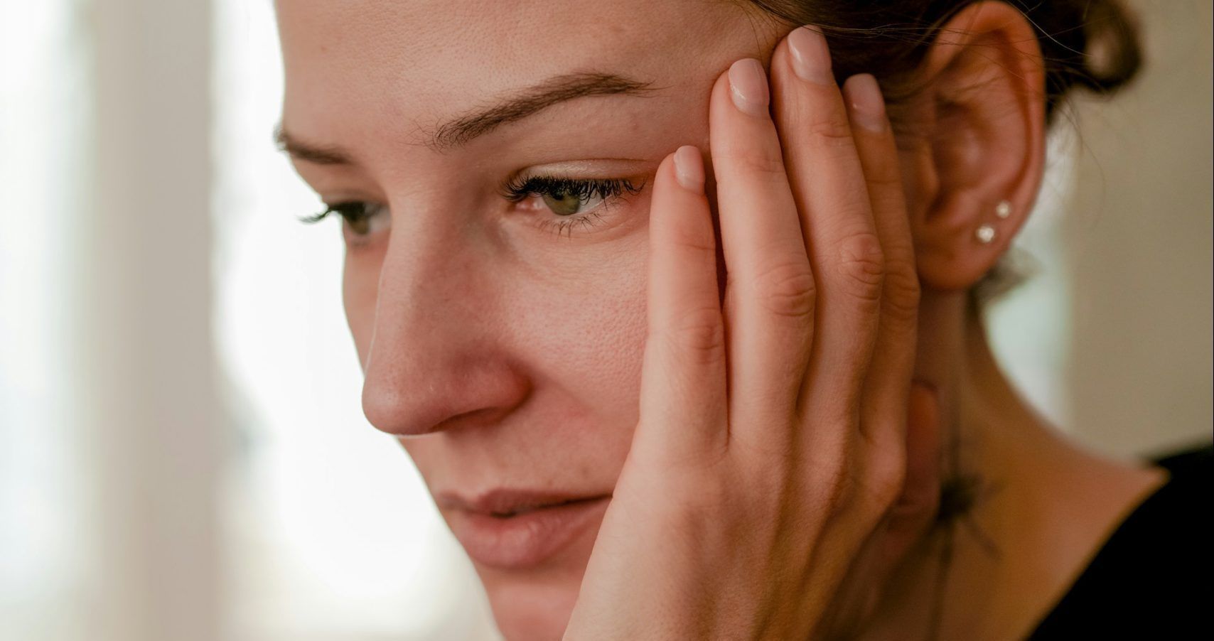 A woman is covering her face with her hand.