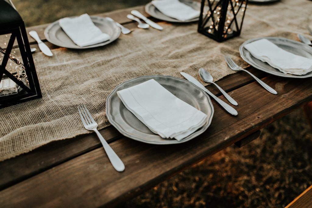 A wooden table with plates , silverware , and napkins on it.