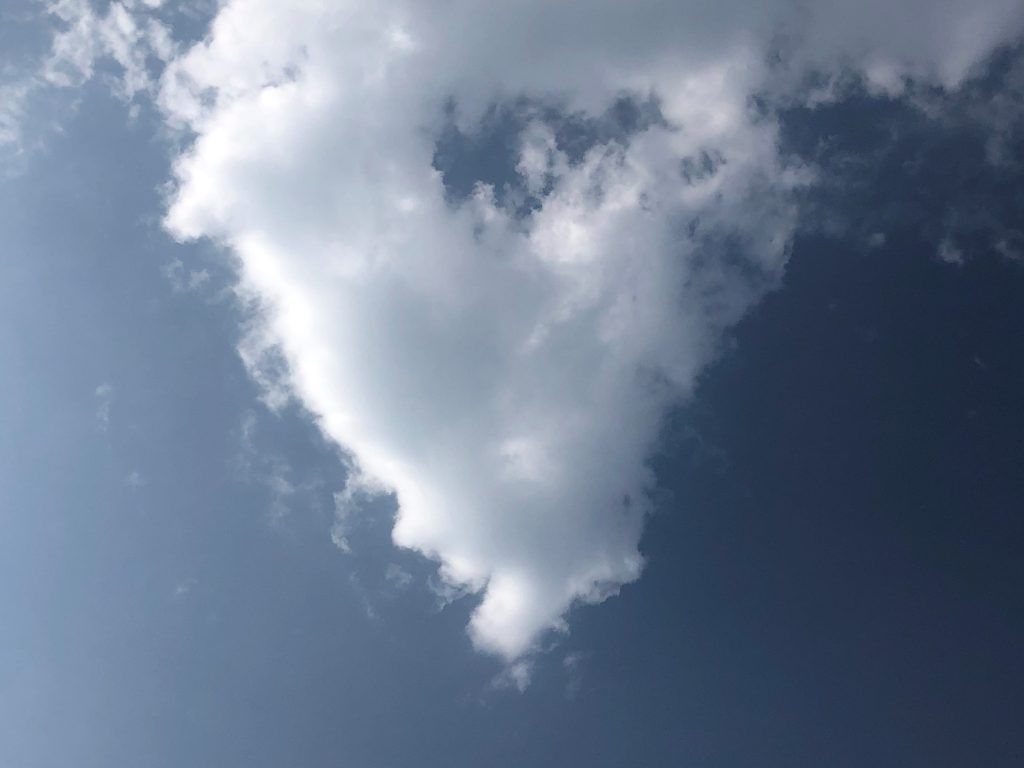 A heart shaped cloud in a blue sky