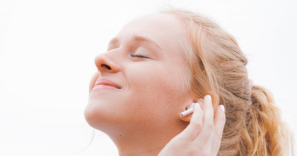 A woman is listening to music with headphones in her ears.