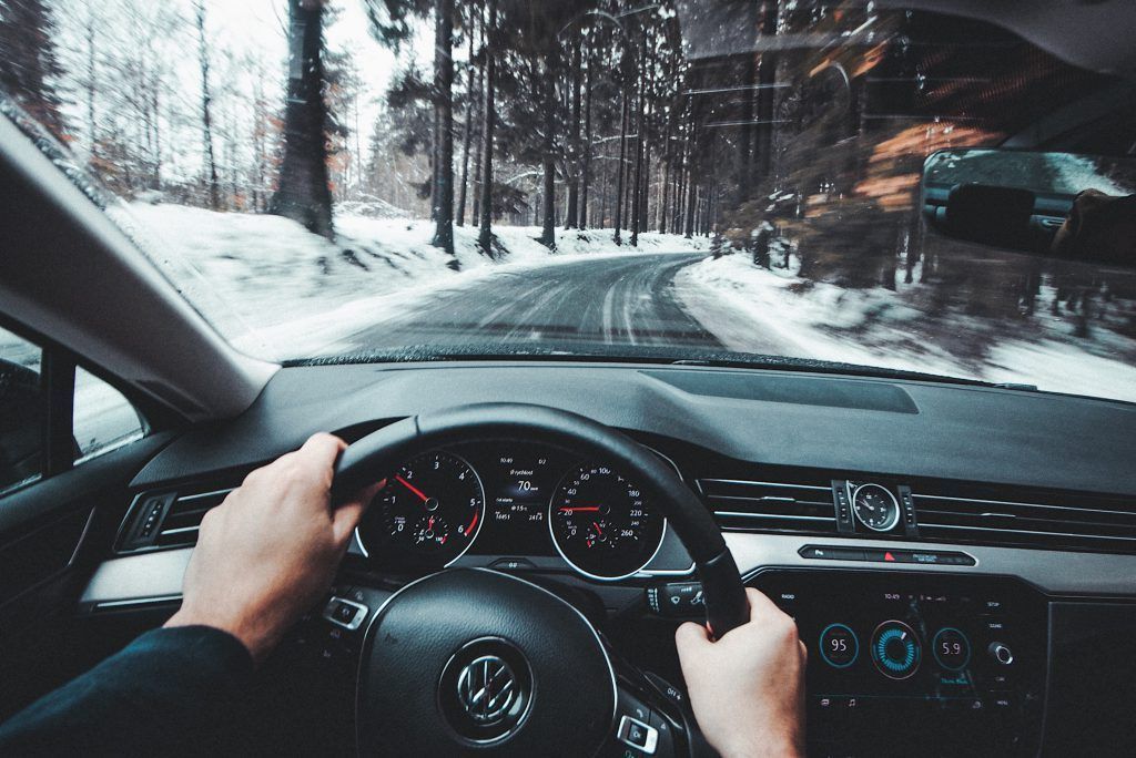 A person is driving a car on a snowy road.