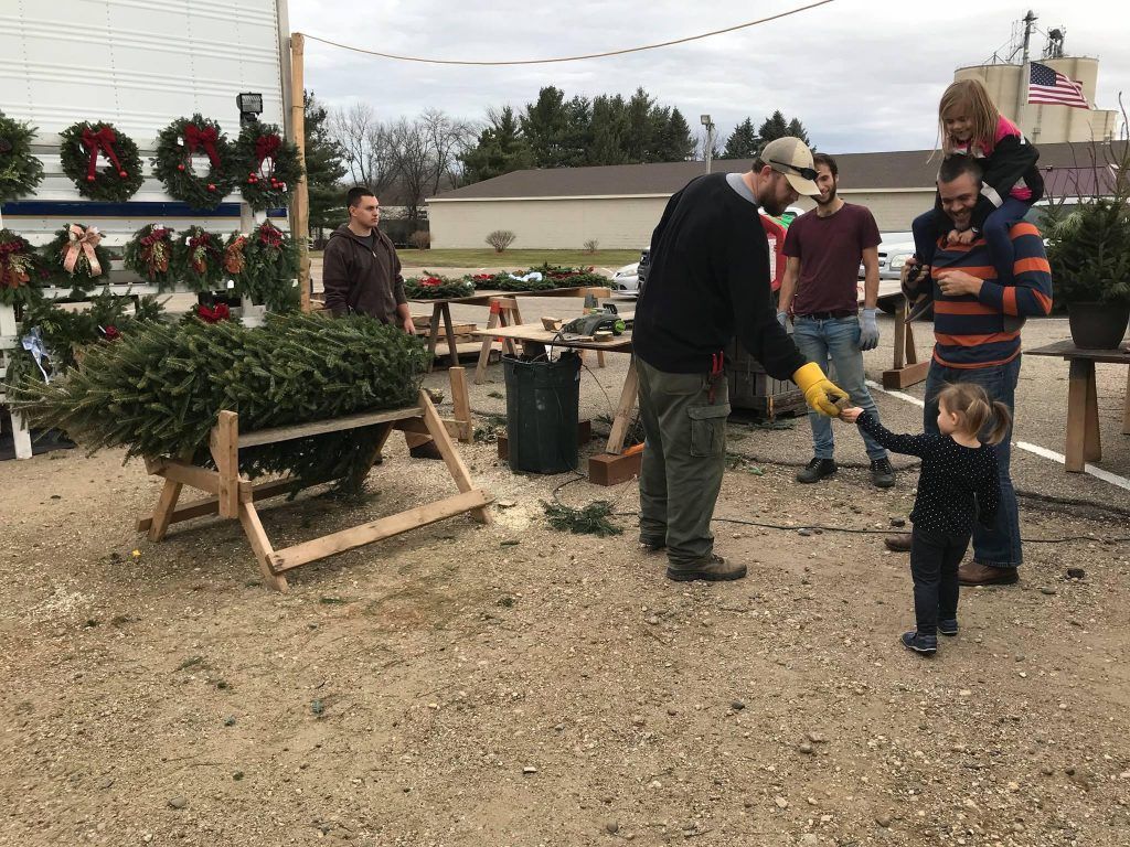 A group of people are standing around a christmas tree.