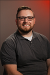 A man with a beard and glasses is smiling for the camera.