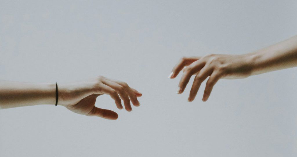 Two people are reaching for each other 's hands.