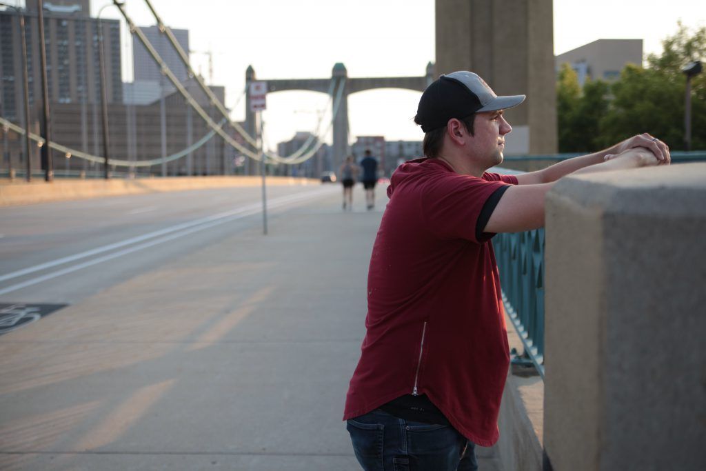 A man leaning on a railing on a bridge