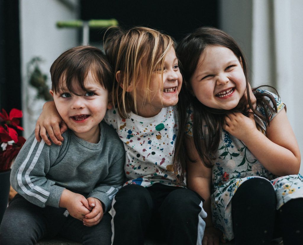 A boy and two girls are sitting next to each other and smiling.