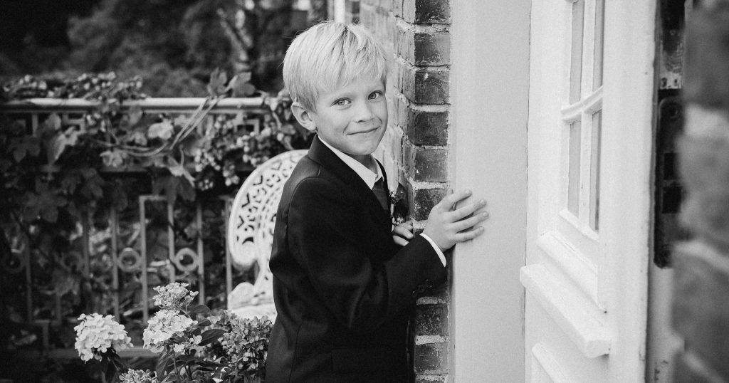 A young boy in a suit and tie is standing in front of a white door.