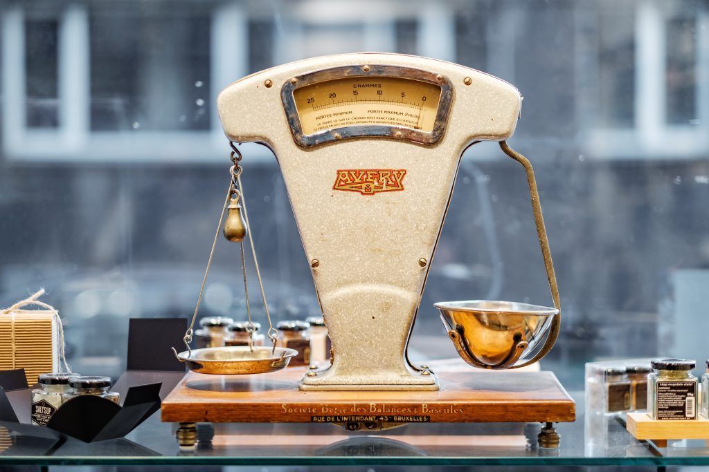 An old scale is sitting on a glass shelf.