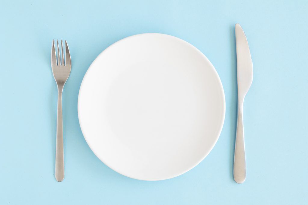 A plate with a knife and a fork on a blue background