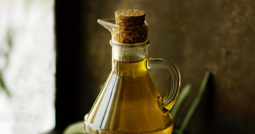 A bottle of olive oil with a cork on top of it.
