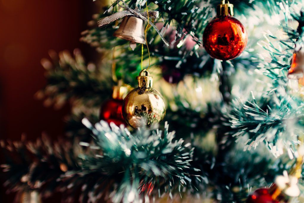 A close up of a christmas tree with decorations hanging from it.