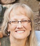 A close up of a woman wearing glasses and smiling.
