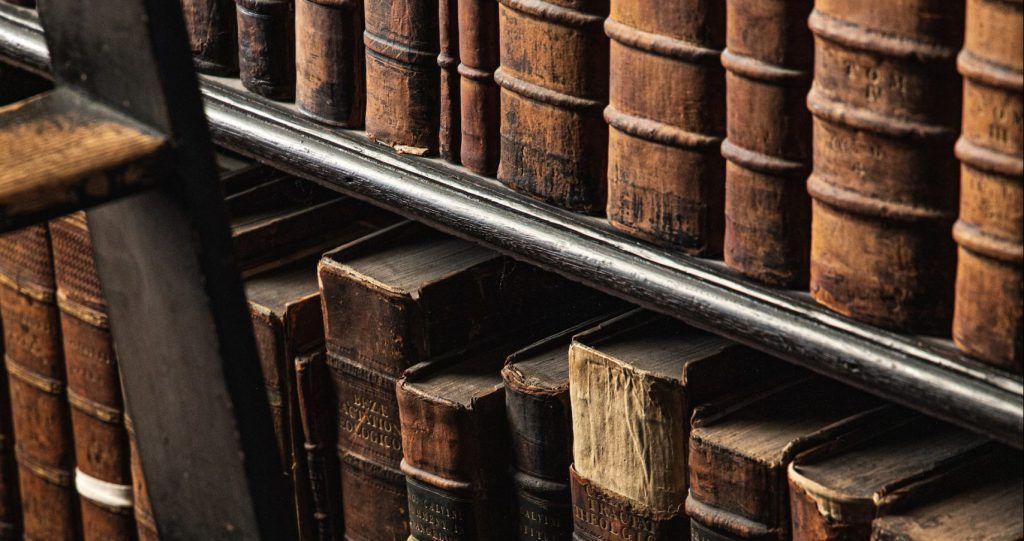 A ladder is sitting next to a shelf of old books.