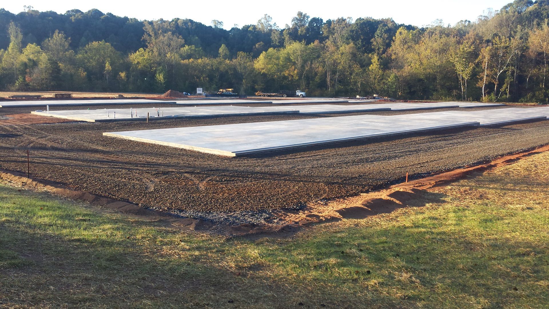 Rectangular water treatment basins lined with white sheeting in a wooded outdoor area