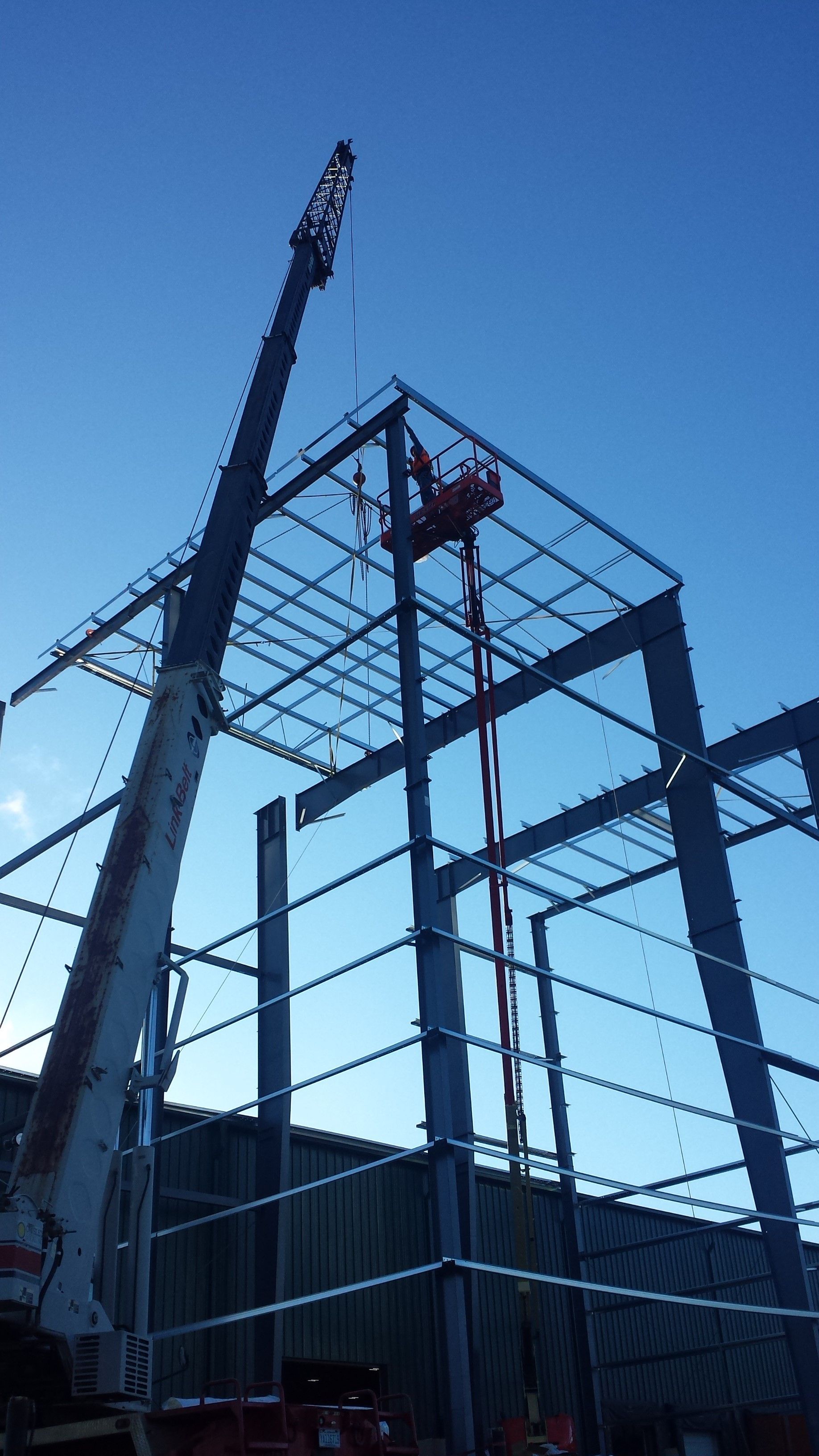 Construction site with steel frame structure and a crane against a blue sky
