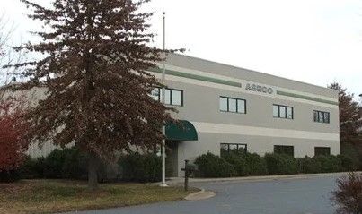 Two-story beige office building with green awnings and a tree in the foreground.