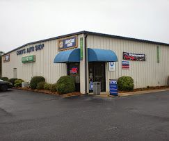 Auto shop exterior with blue awning, beige siding, and parking lot