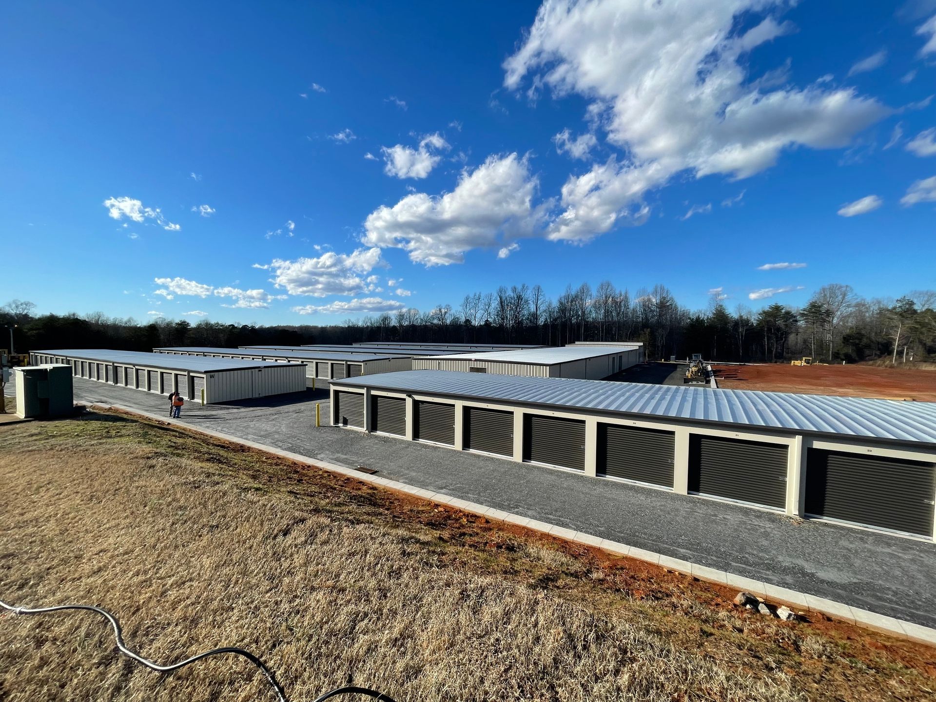 Rooftop HVAC units and vents on a flat industrial roof under a bright blue sky with clouds