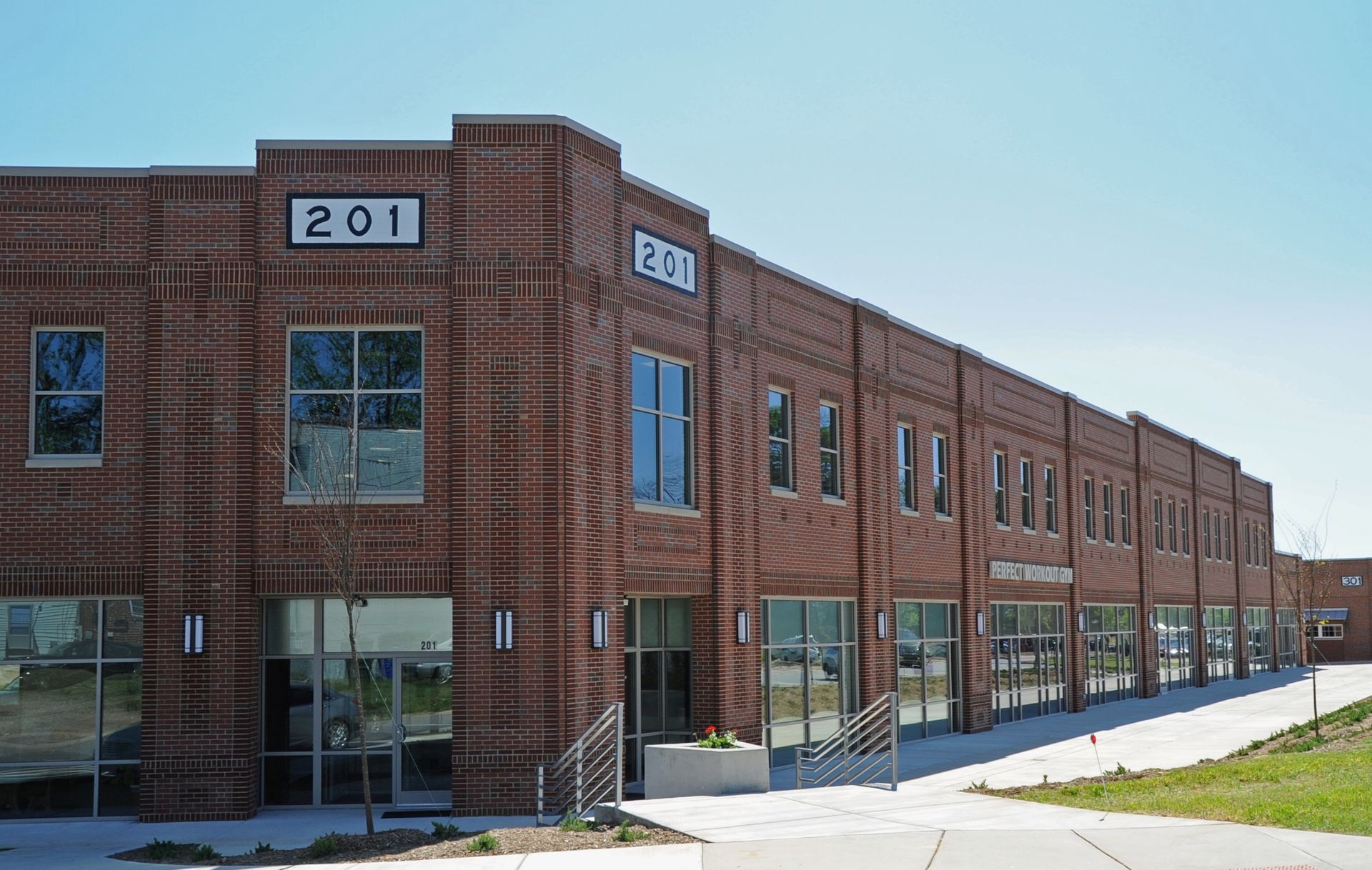 Red brick commercial building with large windows and address number 201 on the corner