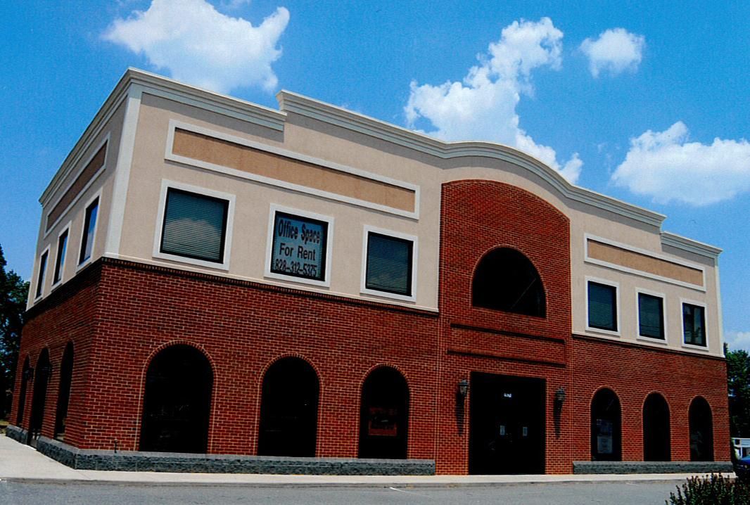 Two-story brick building with arched windows and a cream upper facade under a blue sky