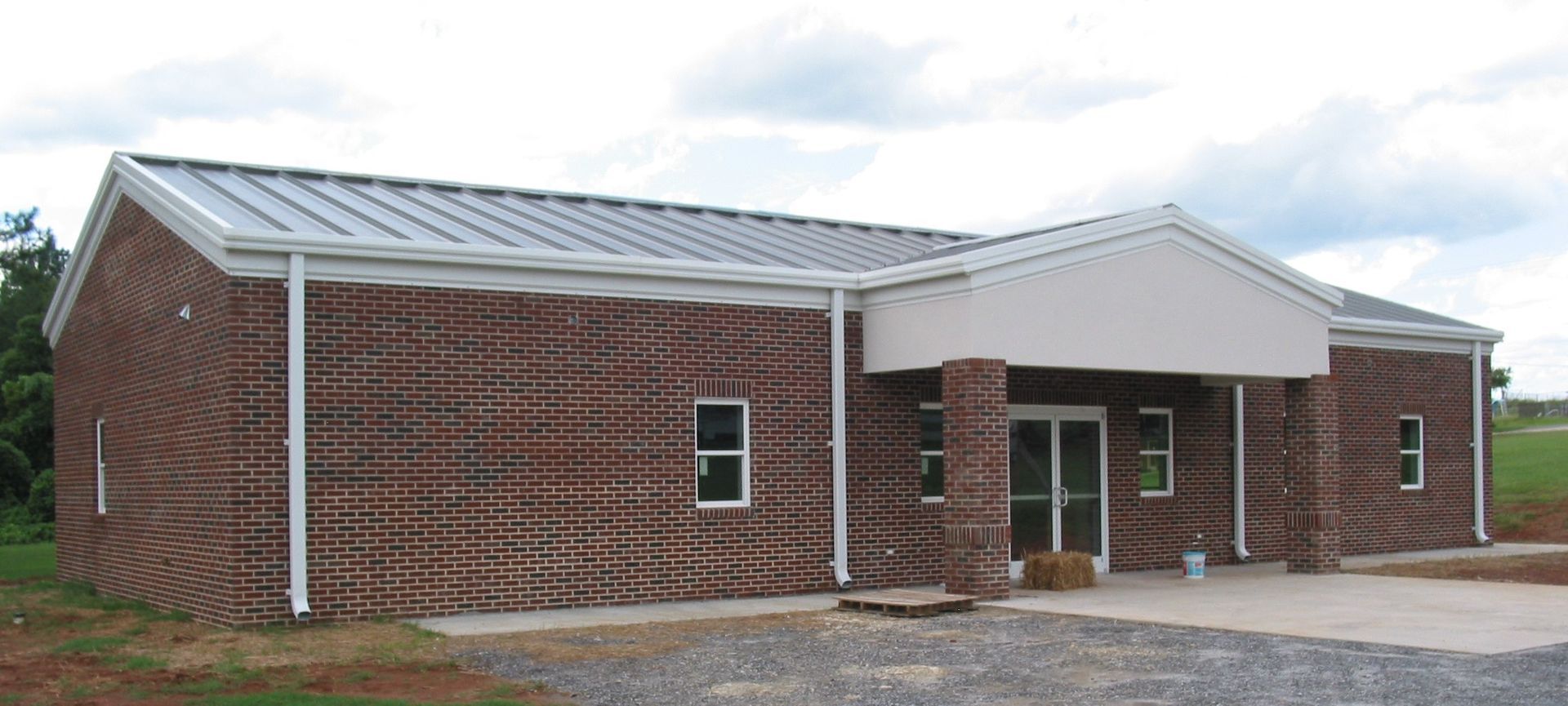 Brick single-story building with white metal roof and small covered entrance.