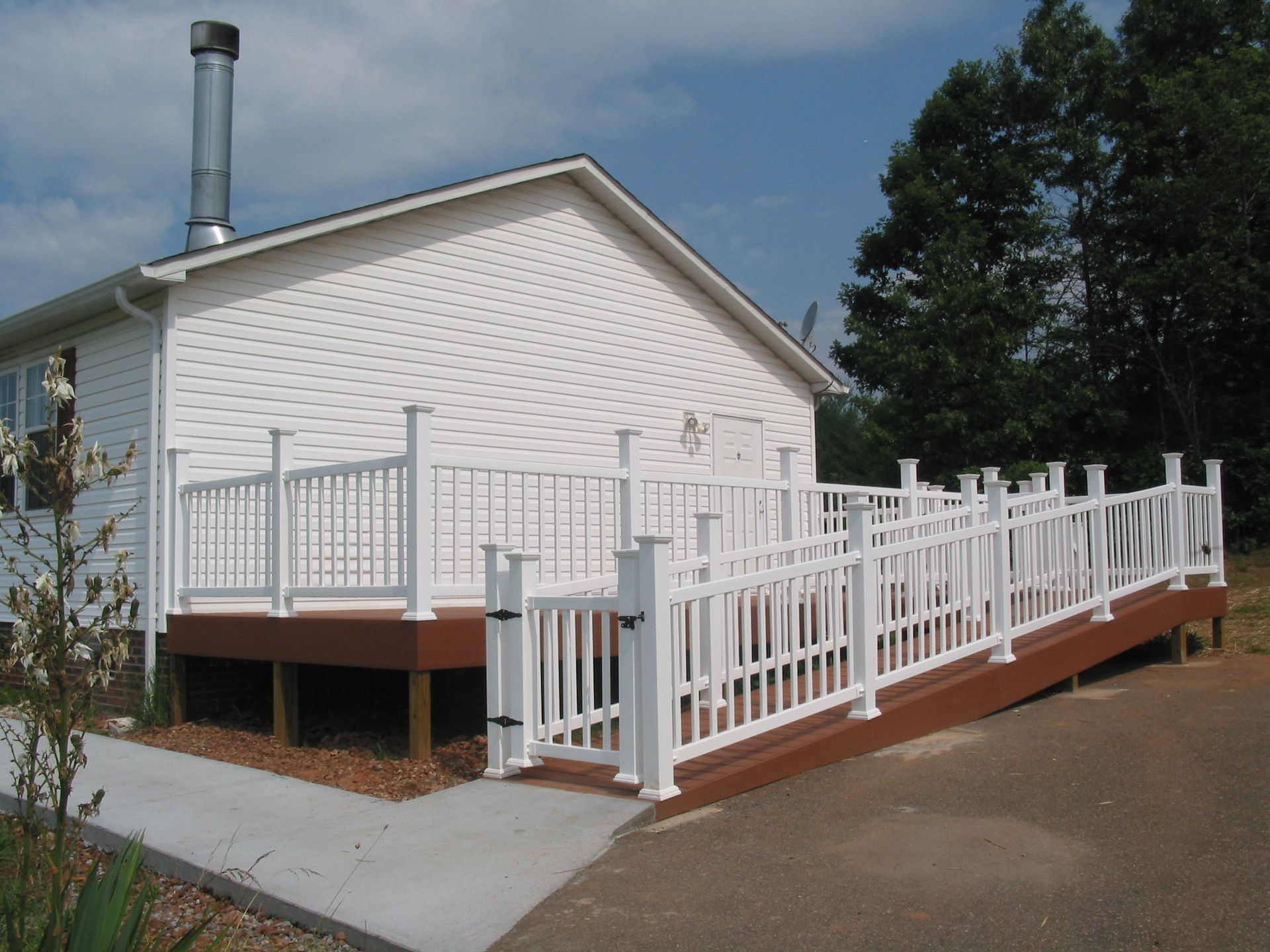 White house with accessible ramp and railing, viewed from the side on a sunny day