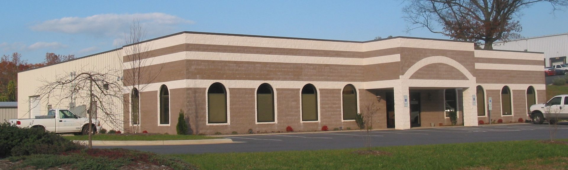 Exterior of a tan brick building with white trim and arched windows under a blue sky