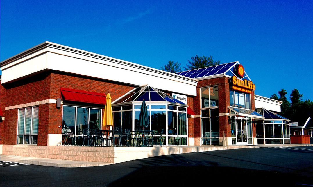 Exterior of a brick restaurant with large windows, white trim, and a sunny parking lot