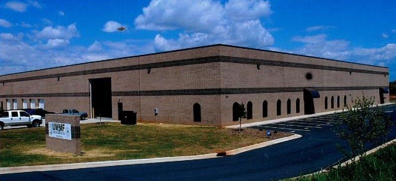 Single-story tan brick building with a parking lot and blue sky