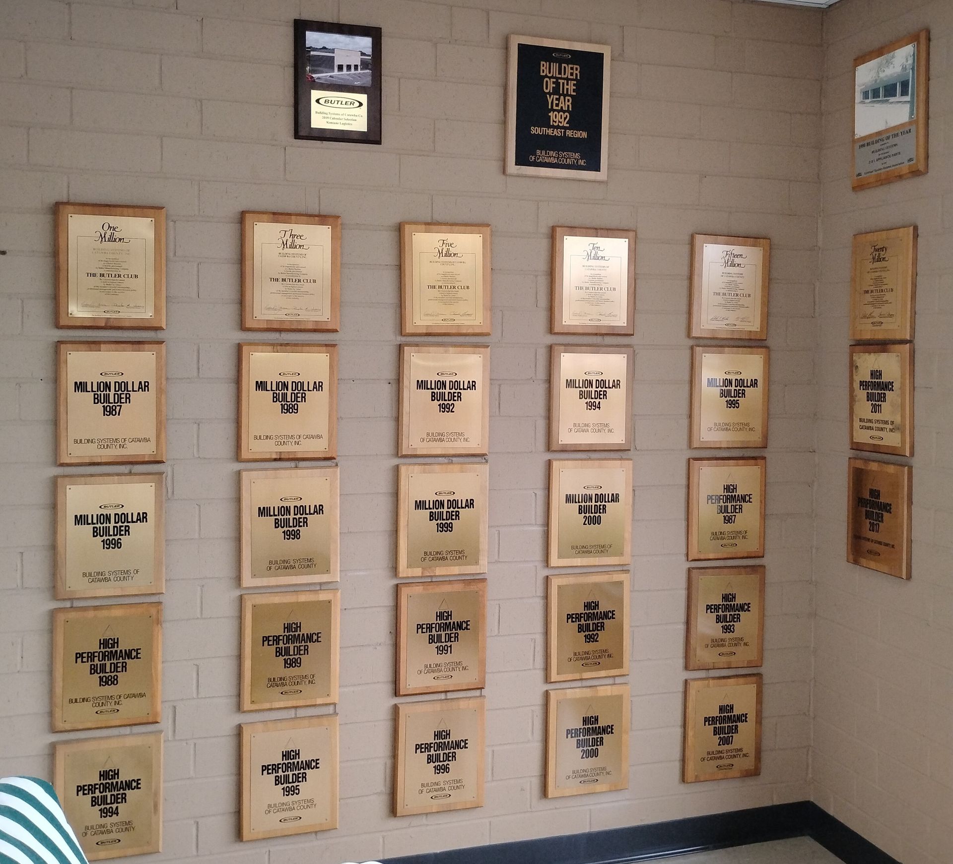 Wall covered with framed plaques and awards in a small indoor display area.