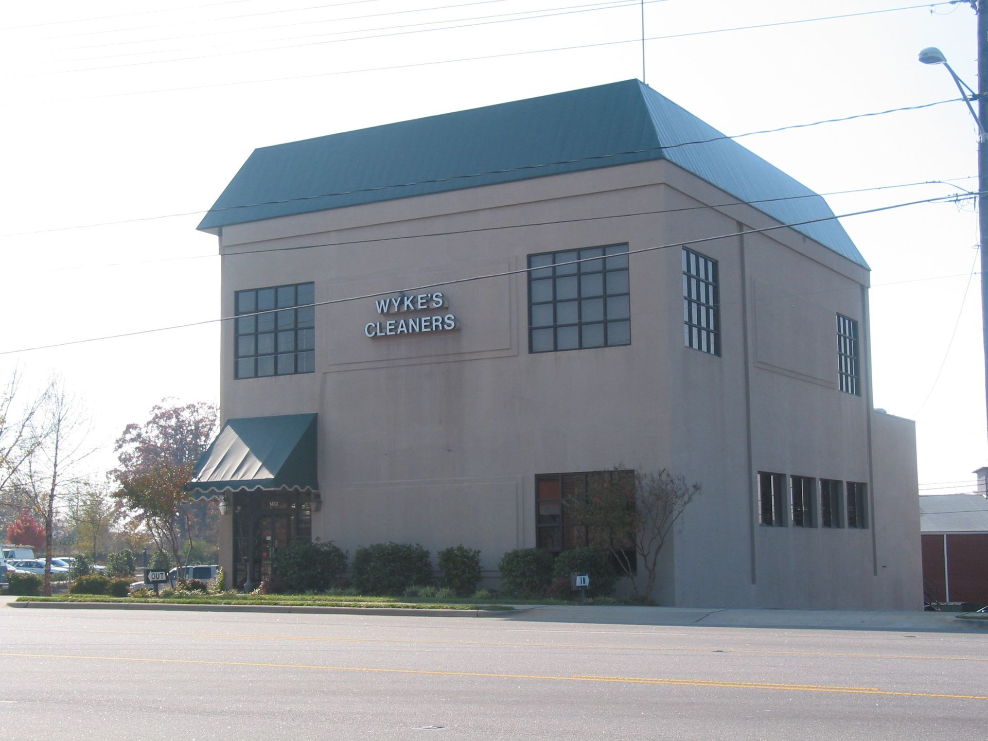 Two-story beige building with teal roof and awning on a street corner