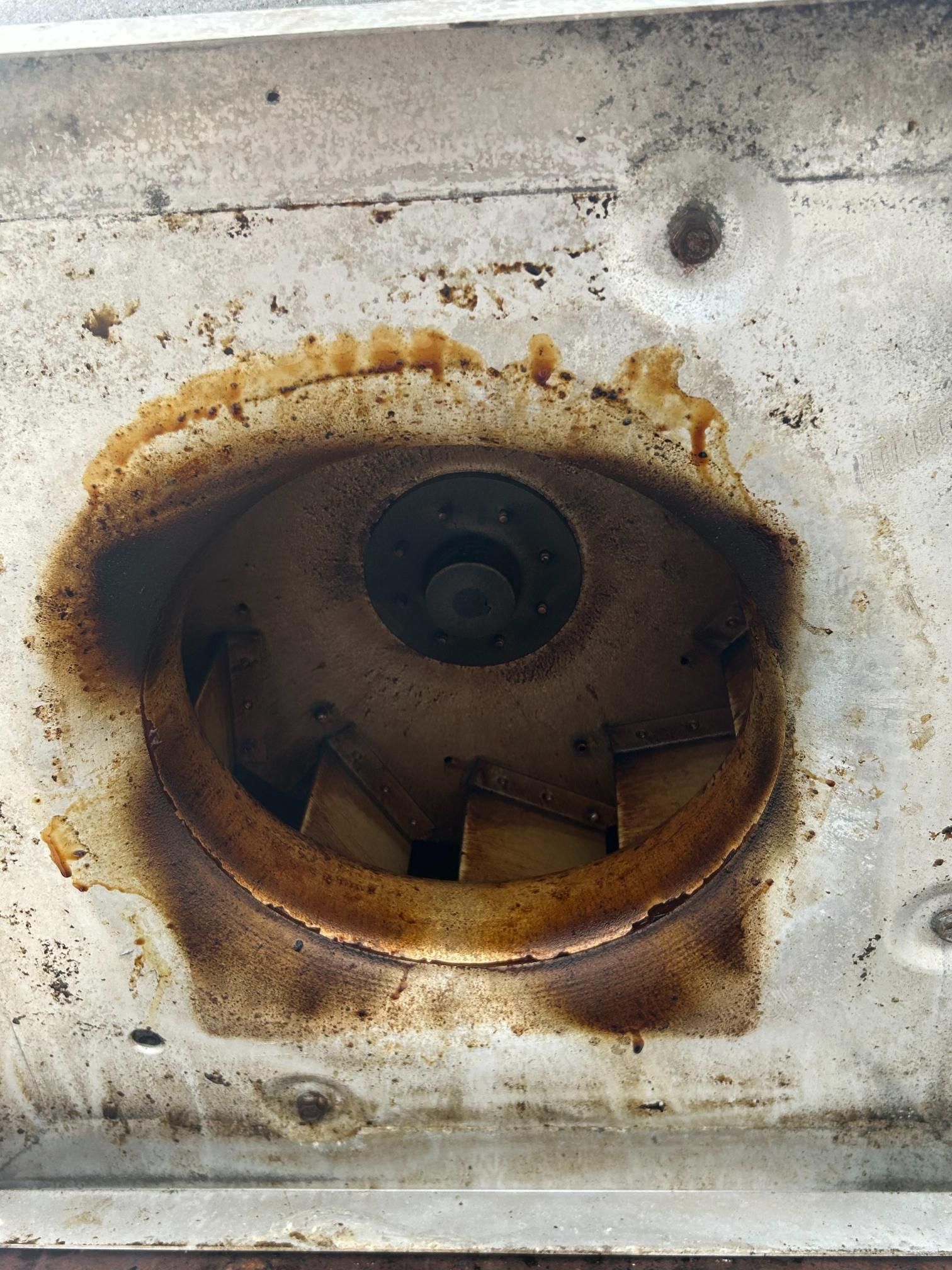 Close-up of a dirty, greasy oven fan with brown residue.