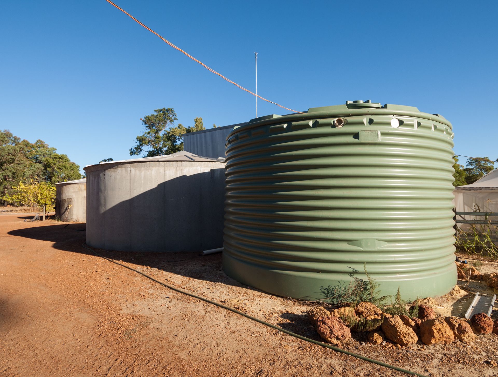 Large green water tank and concrete tank on a farm.