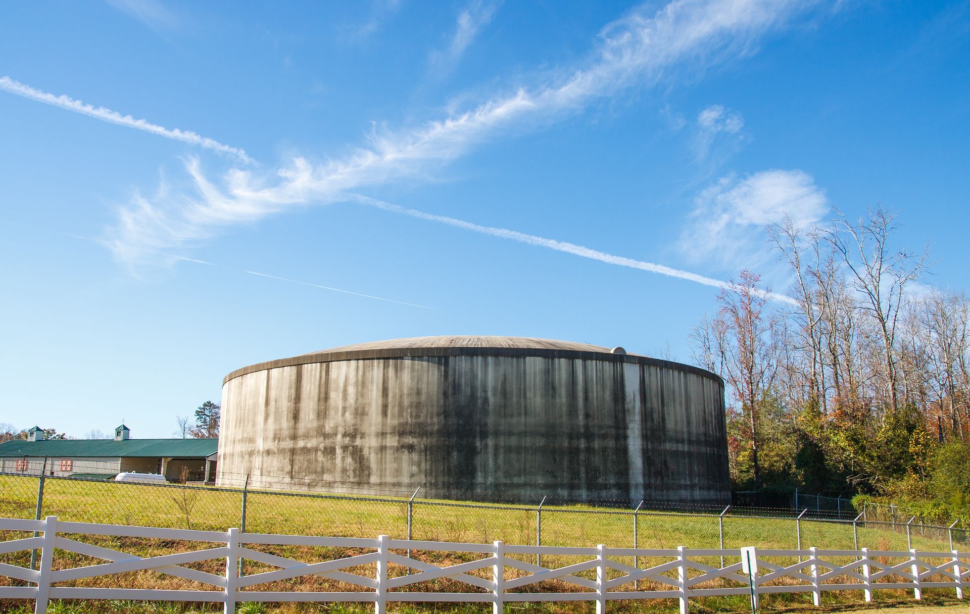 Large round concrete water tank in an open field, storing rainwater efficiently. Large round concrete water tank in an open field, storing rainwater efficiently.