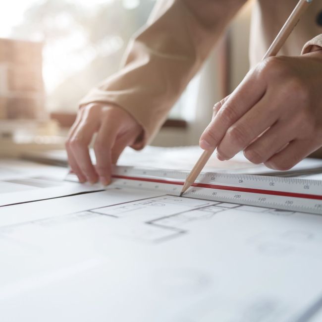 A person is measuring a piece of paper with a ruler and pencil