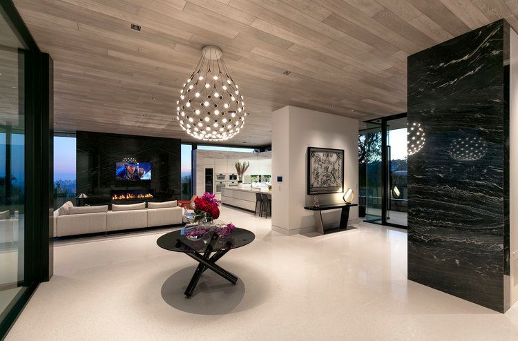 A living room with a table and a chandelier hanging from the ceiling