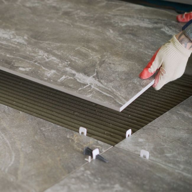 A person is laying a tile on the floor.