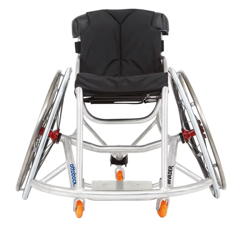Silver wheelchair with black seat and back, orange wheels, indoors.