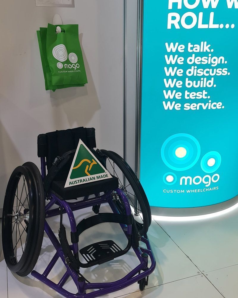 Wheelchair with a green and yellow sign, green bags, and text that says 