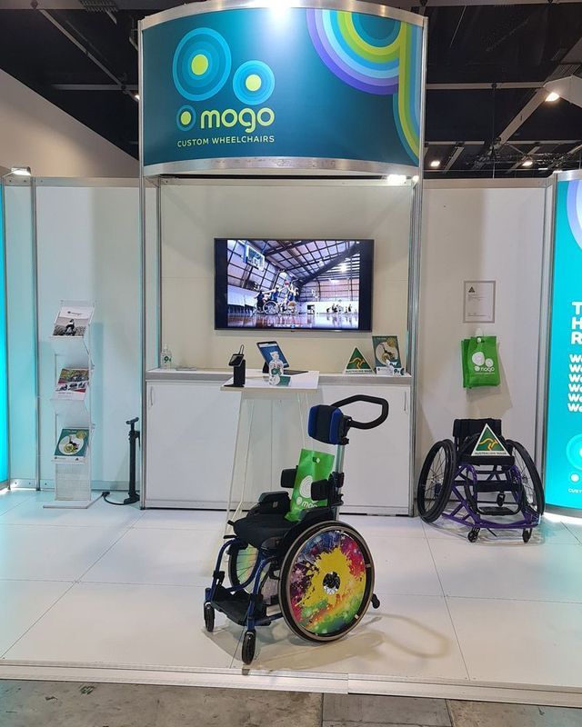 Mogo booth with a wheelchair, a screen, and promotional materials.
