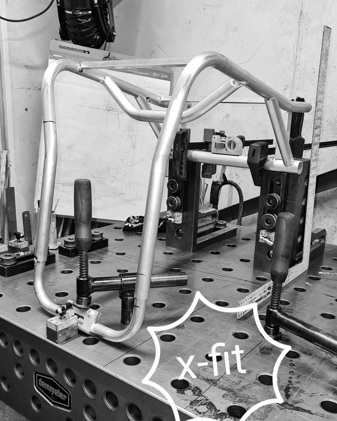 A metal tube frame held in place by clamps on a table; labeled